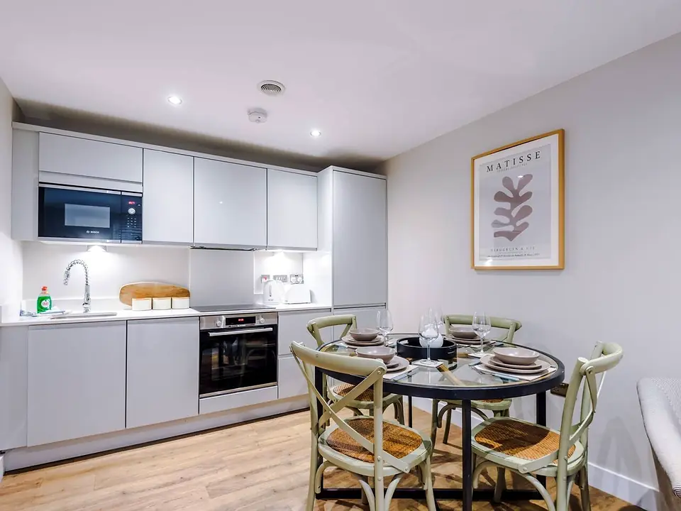 Round dining table set for four in front of a modern grey kitchen