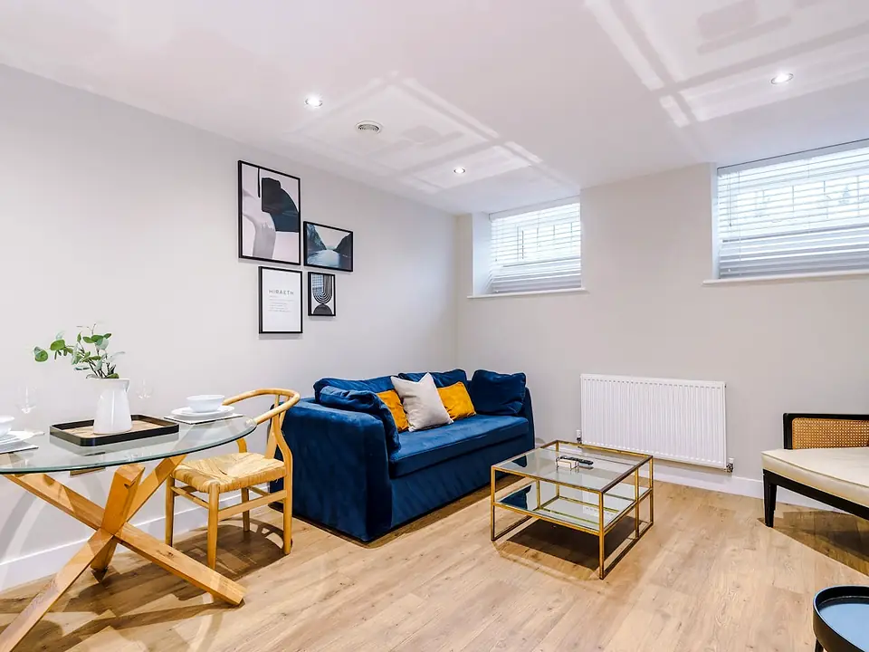 Bright open-plan living and dining room with a navy velvet sofa, a glass dining table and wooden chairs