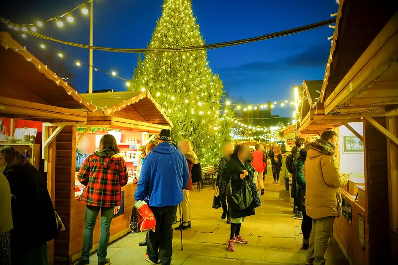 Christmas Market stalls and a lit Christmas tree at dusk by the Town Hall