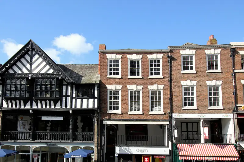Black-and-white and red-brick buildings on Bridge Street above the Rows galleries, with café parasols below